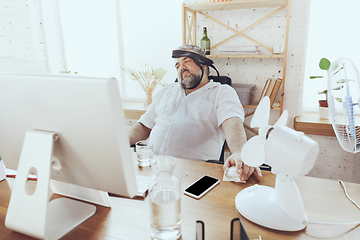 Image showing Businessman, manager in office with computer and fan cooling off, feeling hot, flushed