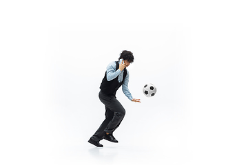 Image showing Man in office clothes playing football or soccer with ball on white background. Unusual look for businessman in motion, action. Sport, healthy lifestyle.