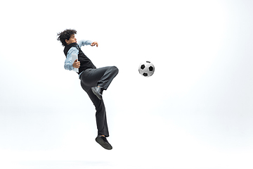 Image showing Man in office clothes playing football or soccer with ball on white background. Unusual look for businessman in motion, action. Sport, healthy lifestyle.