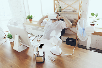 Image showing Businessman, manager in office with computer and fan cooling off, feeling hot, flushed