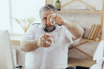 Image showing Businessman, manager in office with computer and fan cooling off, feeling hot, flushed