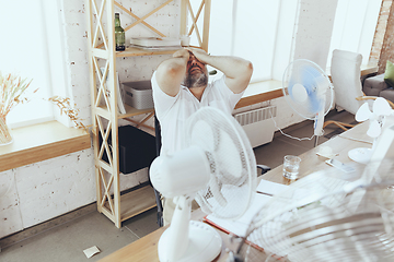 Image showing Businessman, manager in office with computer and fan cooling off, feeling hot, flushed