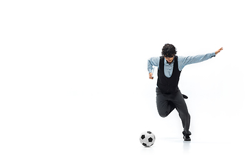 Image showing Man in office clothes playing football or soccer with ball on white background. Unusual look for businessman in motion, action. Sport, healthy lifestyle.