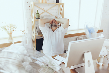 Image showing Businessman, manager in office with computer and fan cooling off, feeling hot, flushed