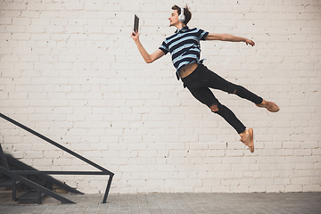 Image showing Jumping young buinessman in front of buildings, on the run in jump high