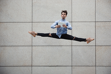 Image showing Jumping young buinessman in front of buildings, on the run in jump high