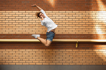 Image showing Jumping young man in front of buildings, on the run in jump high