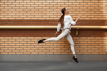 Image showing Jumping young woman in front of buildings, on the run in jump high