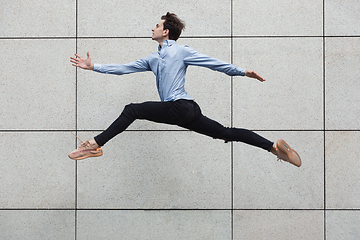 Image showing Jumping young buinessman in front of buildings, on the run in jump high