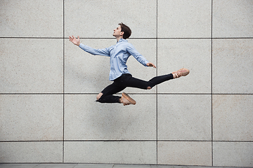 Image showing Jumping young buinessman in front of buildings, on the run in jump high