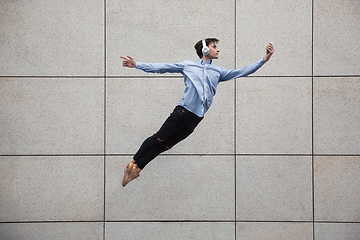 Image showing Jumping young buinessman in front of buildings, on the run in jump high