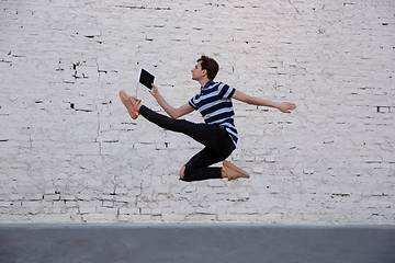 Image showing Jumping young buinessman in front of buildings, on the run in jump high