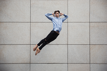 Image showing Jumping young buinessman in front of buildings, on the run in jump high