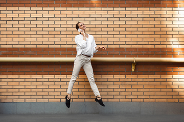 Image showing Jumping young woman in front of buildings, on the run in jump high