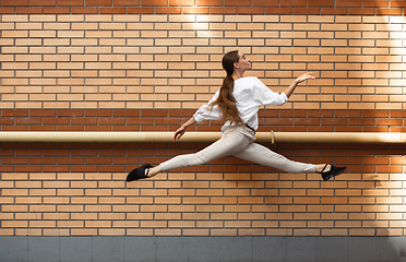 Image showing Jumping young woman in front of buildings, on the run in jump high