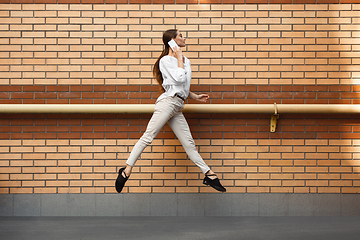 Image showing Jumping young woman in front of buildings, on the run in jump high