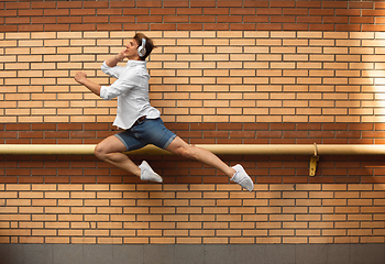 Image showing Jumping young man in front of buildings, on the run in jump high