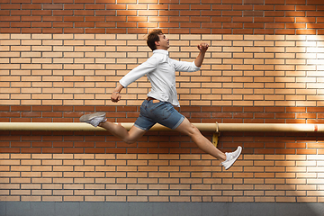 Image showing Jumping young man in front of buildings, on the run in jump high