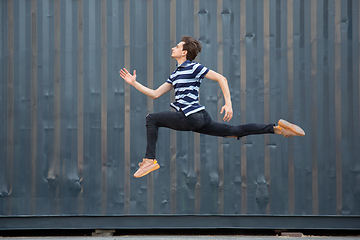 Image showing Jumping young buinessman in front of buildings, on the run in jump high