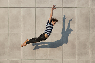 Image showing Jumping young buinessman in front of buildings, on the run in jump high