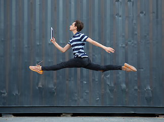 Image showing Jumping young buinessman in front of buildings, on the run in jump high