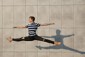 Image showing Jumping young buinessman in front of buildings, on the run in jump high