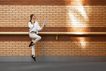 Image showing Jumping young woman in front of buildings, on the run in jump high