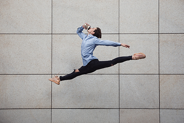 Image showing Jumping young buinessman in front of buildings, on the run in jump high