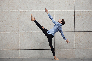 Image showing Jumping young buinessman in front of buildings, on the run in jump high