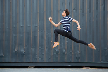 Image showing Jumping young buinessman in front of buildings, on the run in jump high