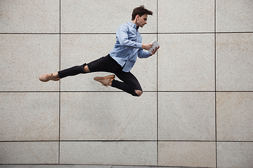 Image showing Jumping young buinessman in front of buildings, on the run in jump high