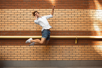 Image showing Jumping young man in front of buildings, on the run in jump high