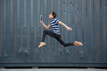 Image showing Jumping young buinessman in front of buildings, on the run in jump high