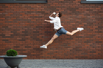 Image showing Jumping young man in front of buildings, on the run in jump high