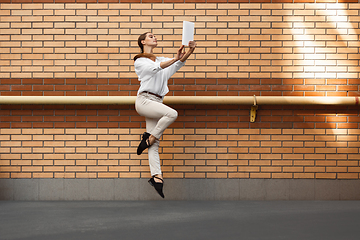 Image showing Jumping young woman in front of buildings, on the run in jump high