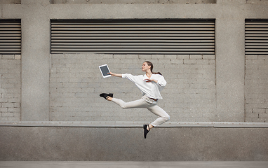 Image showing Jumping young woman in front of buildings, on the run in jump high