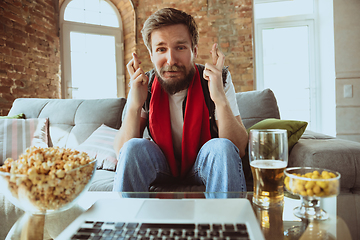 Image showing Excited football fan watching sport match at home, remote support of favourite team during coronavirus pandemic outbreak