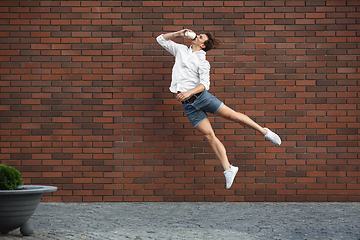 Image showing Jumping young man in front of buildings, on the run in jump high