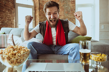 Image showing Excited football fan watching sport match at home, remote support of favourite team during coronavirus pandemic outbreak