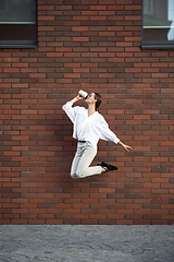 Image showing Jumping young woman in front of buildings, on the run in jump high