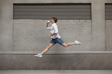 Image showing Jumping young man in front of buildings, on the run in jump high