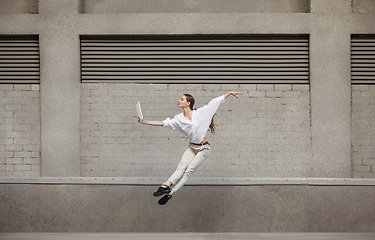 Image showing Jumping young woman in front of buildings, on the run in jump high