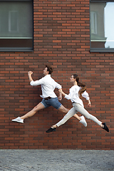 Image showing Jumping young couple in front of buildings, on the run in jump high