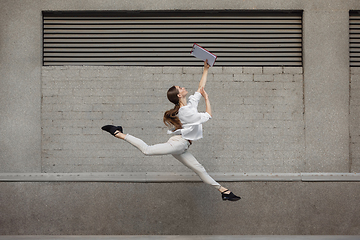 Image showing Jumping young woman in front of buildings, on the run in jump high