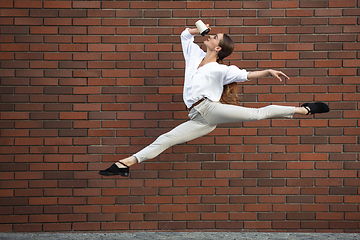 Image showing Jumping young woman in front of buildings, on the run in jump high