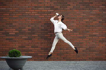 Image showing Jumping young woman in front of buildings, on the run in jump high