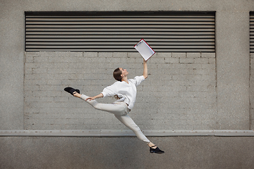 Image showing Jumping young woman in front of buildings, on the run in jump high