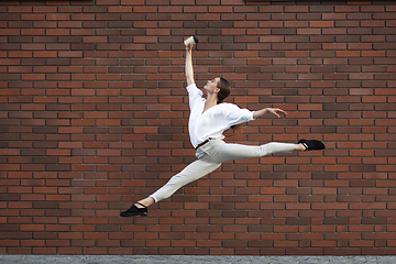 Image showing Jumping young woman in front of buildings, on the run in jump high