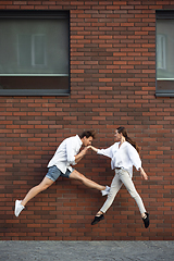 Image showing Jumping young couple in front of buildings, on the run in jump high