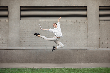 Image showing Jumping young woman in front of buildings, on the run in jump high